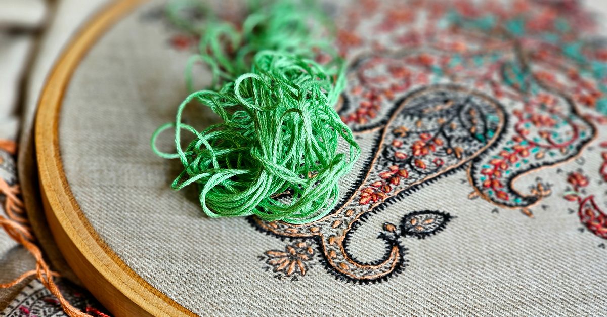 Gros plan sur la broderie d'un coussin montrant une frise de losanges et de rosaces.