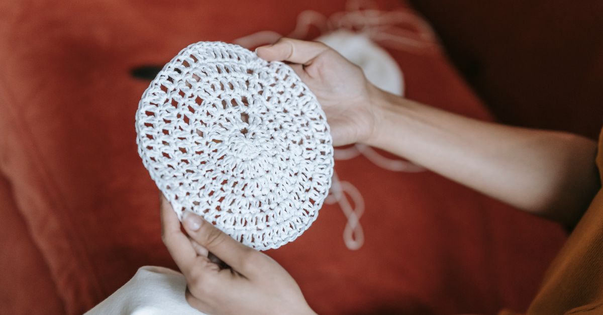 Mains tenant un textile délicat au-dessus d'une bassine d'eau tiède, dans une lumière naturelle.